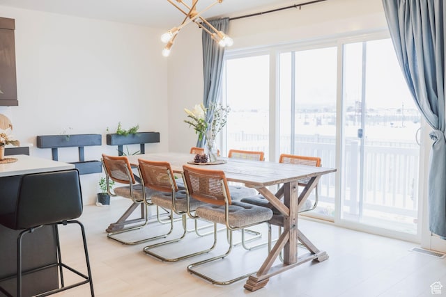 dining room with an inviting chandelier, visible vents, light wood-type flooring, and a wealth of natural light