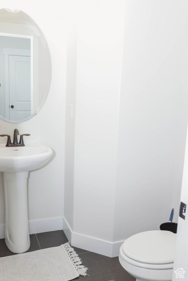 half bathroom with a sink, baseboards, and toilet