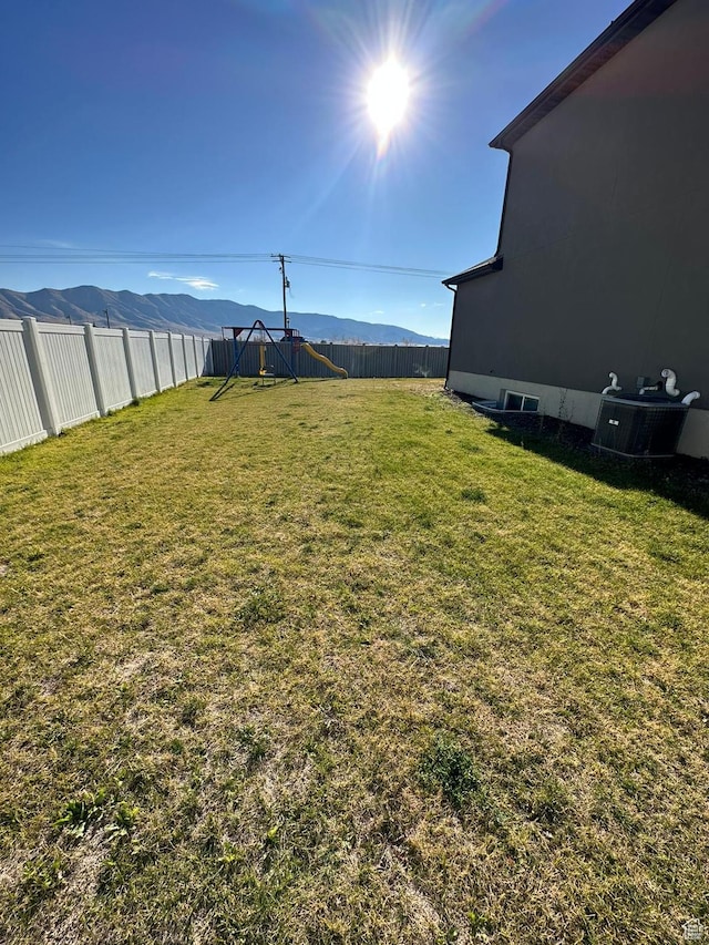 view of yard featuring central air condition unit, a fenced backyard, and a mountain view