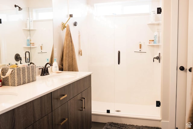 full bathroom with double vanity, a shower stall, and a sink
