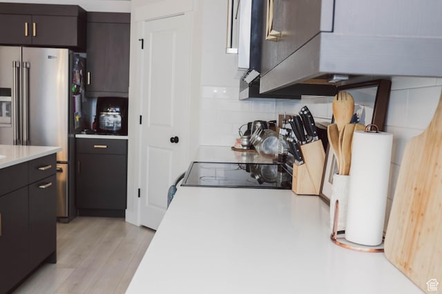 kitchen featuring light countertops, tasteful backsplash, light wood-style floors, and high end fridge