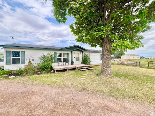 back of property with a deck, fence, and a lawn