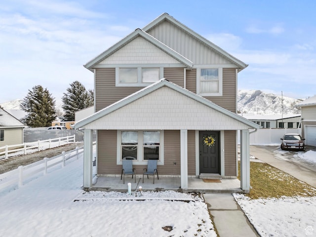 view of front of home with a mountain view, covered porch, and fence