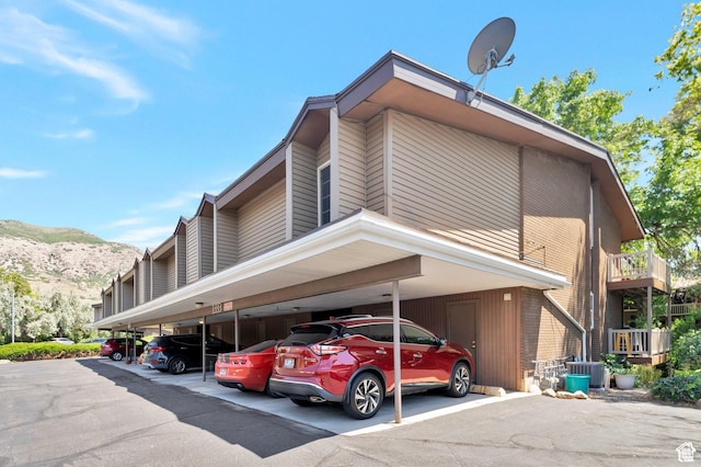 view of building exterior with a mountain view, covered parking, and cooling unit