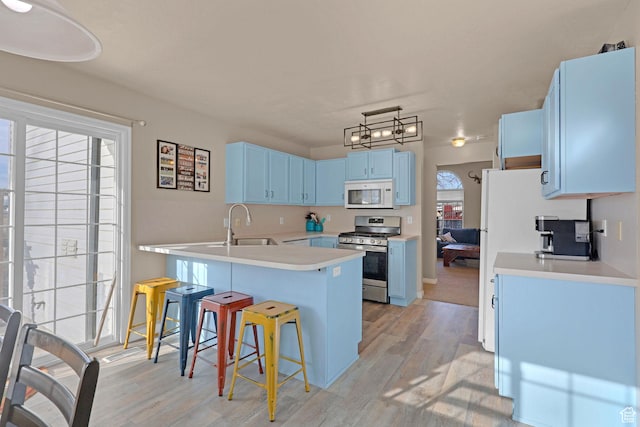 518 W 1330 N, Logan, UT 84341 - kitchen with stainless steel range with gas cooktop, white microwave, blue cabinetry, a kitchen breakfast bar, and light wood-style flooring