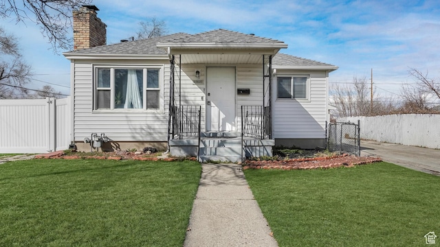 bungalow-style house featuring a front lawn, fence, a chimney, and a shingled roof