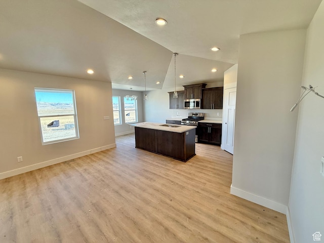 18046 N 6000 W, Riverside, UT 84334 - kitchen with light wood-style flooring, a kitchen island, dark brown cabinetry, appliances with stainless steel finishes, and light countertops