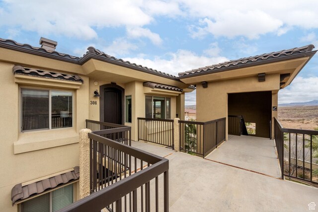doorway to property featuring stucco siding, a tile roof, and a balcony