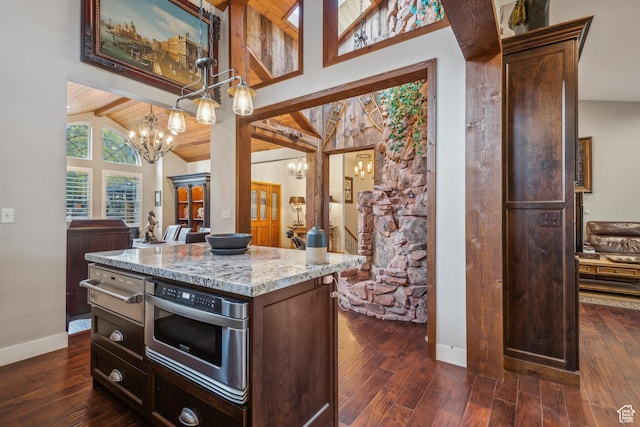 kitchen featuring dark wood-style floors, beamed ceiling, an inviting chandelier, and light stone countertops