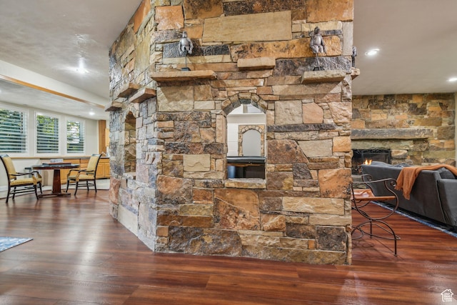 details with a stone fireplace, recessed lighting, wood finished floors, and arched walkways