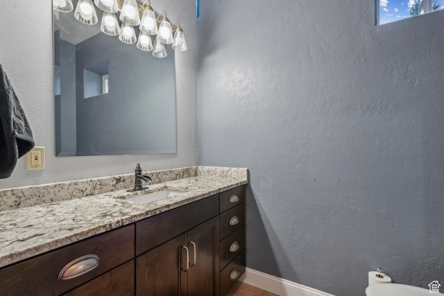 bathroom with vanity, a textured wall, and baseboards