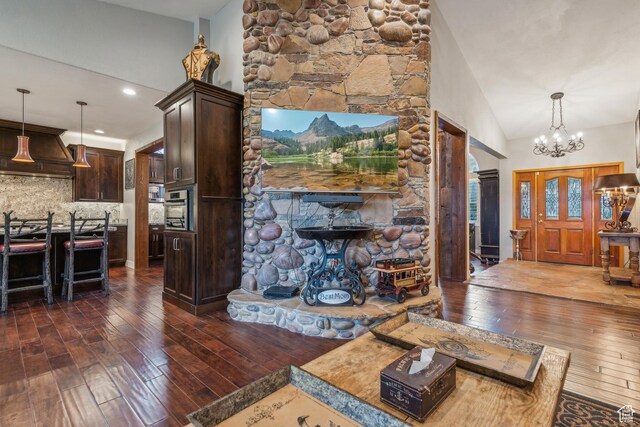 living room with an inviting chandelier, dark wood-style flooring, and high vaulted ceiling
