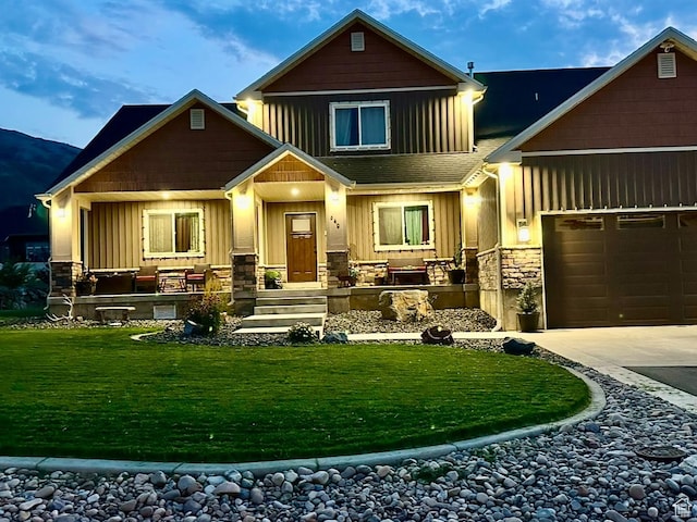 view of front facade with stone siding, board and batten siding, concrete driveway, and a front yard