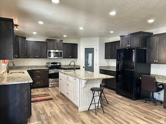 640 S 100 E, Mantua, UT 84324 - kitchen with light stone countertops, light wood finished floors, an island with sink, a sink, and stainless steel appliances