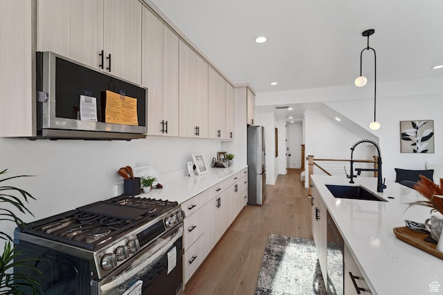 603 N Darwin St E Unit 10, Salt Lake City, UT 84103 - kitchen with modern cabinets, a sink, decorative light fixtures, stainless steel appliances, and light wood-style floors