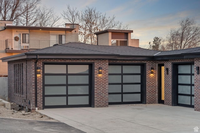 603 N Darwin St E Unit 10, Salt Lake City, UT 84103 - view of front facade featuring a balcony, driveway, a shingled roof, a garage, and brick siding