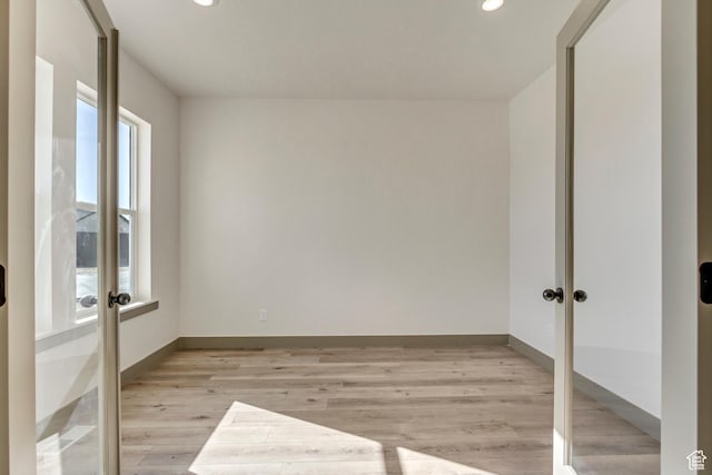empty room with recessed lighting, french doors, light wood-type flooring, and baseboards