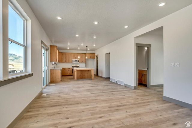 kitchen featuring light wood-type flooring, visible vents, open floor plan, and light countertops