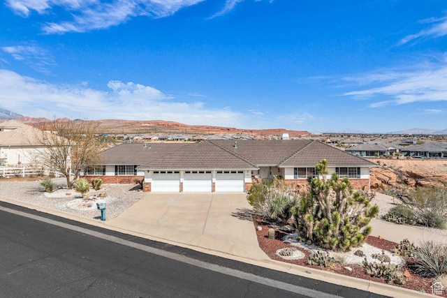 single story home featuring stucco siding, driveway, a tile roof, a mountain view, and a garage