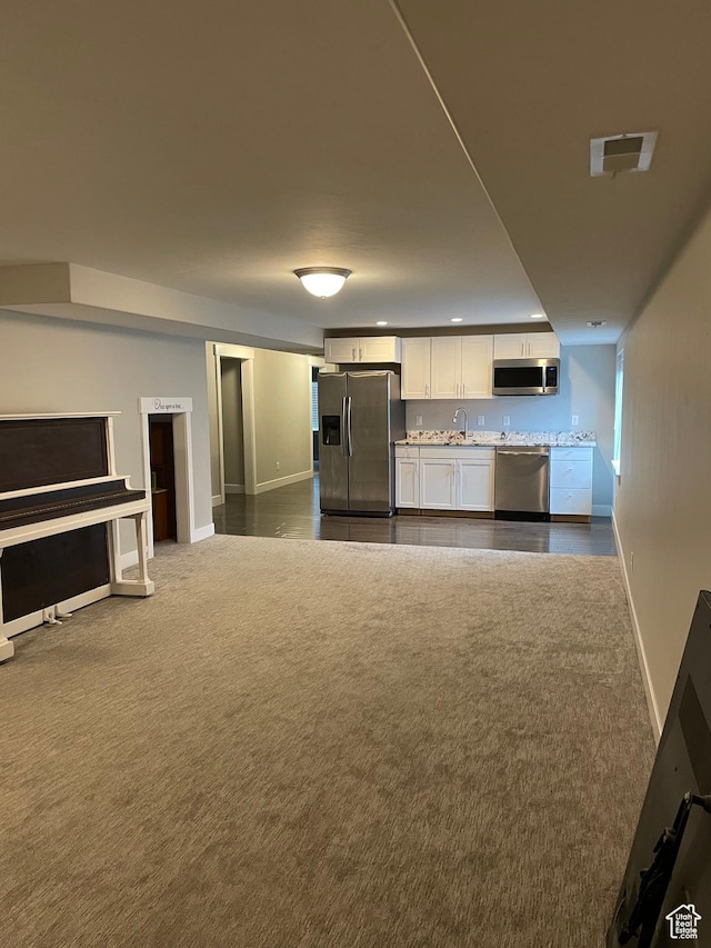 kitchen with visible vents, open floor plan, appliances with stainless steel finishes, white cabinets, and dark colored carpet
