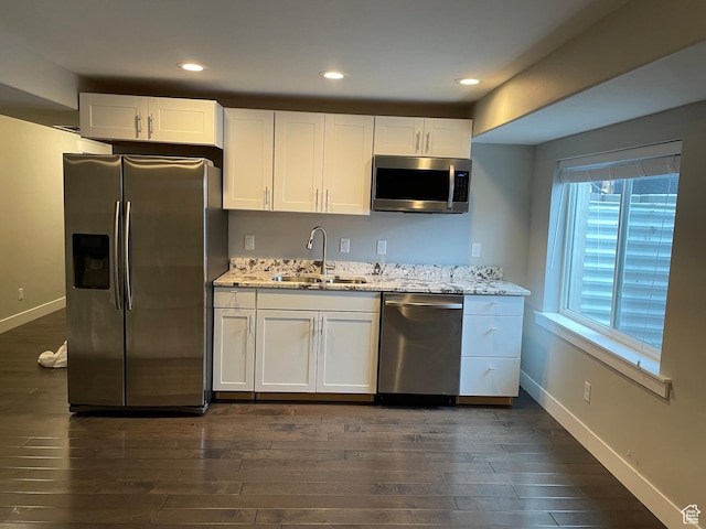 kitchen with a sink, stainless steel appliances, baseboards, and white cabinets