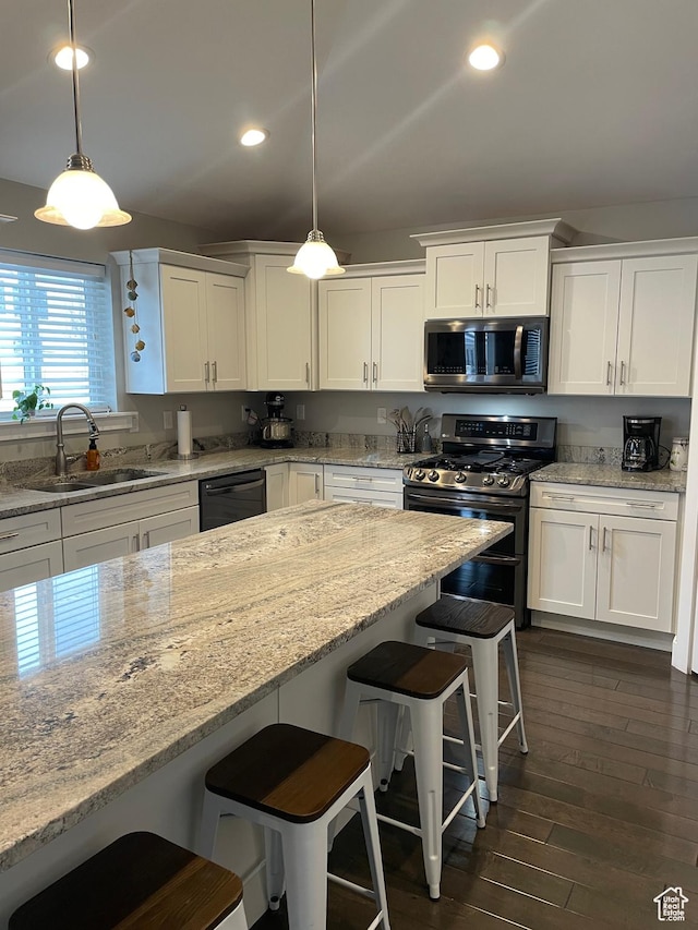 kitchen featuring a sink, a kitchen bar, white cabinets, stainless steel appliances, and dark wood-style flooring