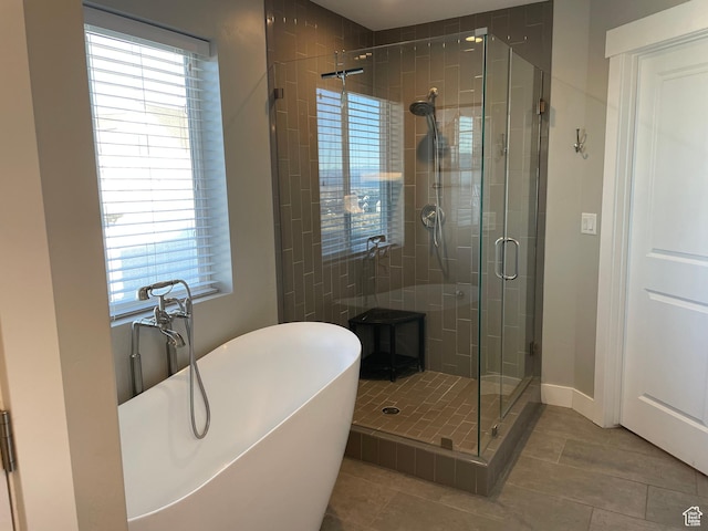 full bath featuring tile patterned floors, a freestanding tub, baseboards, and a stall shower