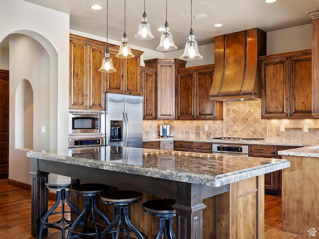 946 S Meadow Lark Ln E, Huntsville, UT 84317 - kitchen with a breakfast bar area, stainless steel appliances, backsplash, dark wood-style floors, and custom exhaust hood