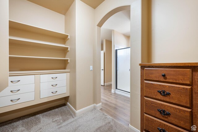 interior space with baseboards, arched walkways, and light carpet