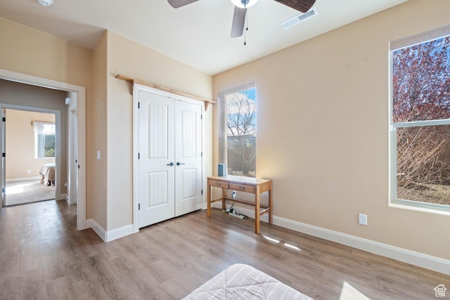 bedroom featuring wood finished floors, visible vents, a closet, and baseboards