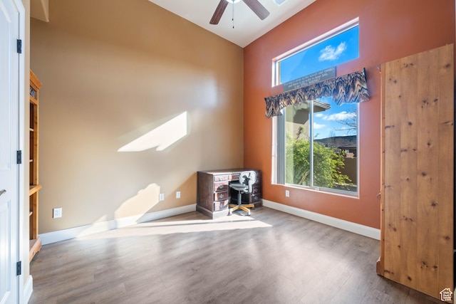 unfurnished office featuring ceiling fan, baseboards, and wood finished floors