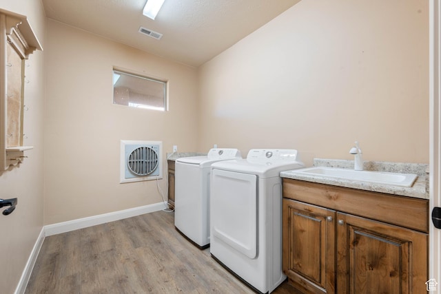 laundry area with baseboards, visible vents, light wood-style flooring, a sink, and washer and clothes dryer