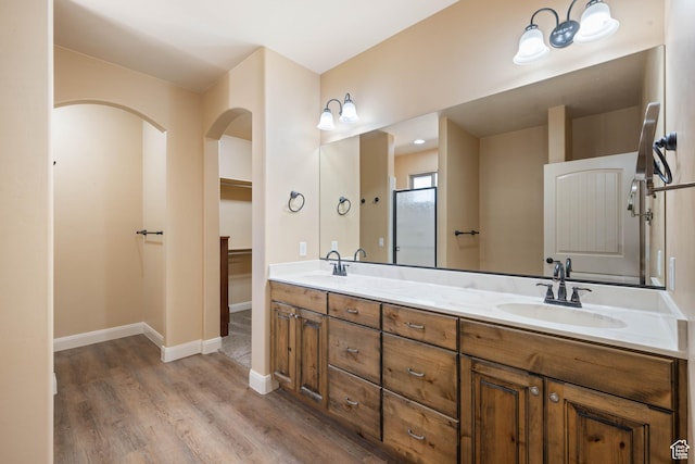 bathroom featuring double vanity, wood finished floors, baseboards, and a sink