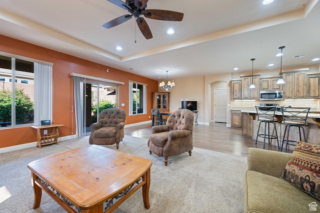 living area featuring a raised ceiling, recessed lighting, a healthy amount of sunlight, and arched walkways