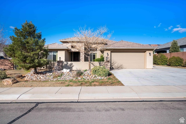 view of front of house featuring stucco siding, concrete driveway, a garage, and fence