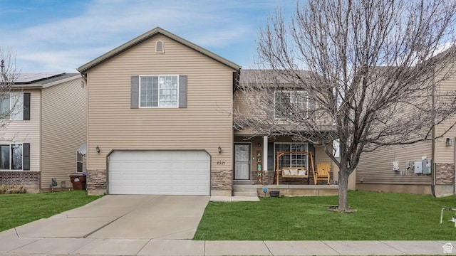 traditional-style house with an attached garage, a porch, concrete driveway, and a front lawn