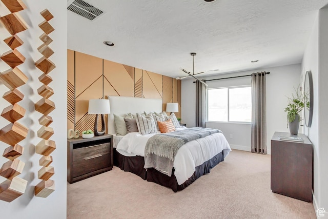 bedroom with light colored carpet, visible vents, and a textured ceiling