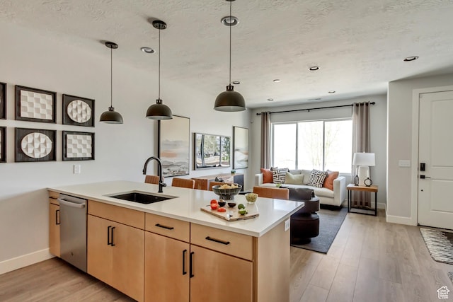 kitchen featuring light wood finished floors, light brown cabinets, light countertops, a peninsula, and a sink