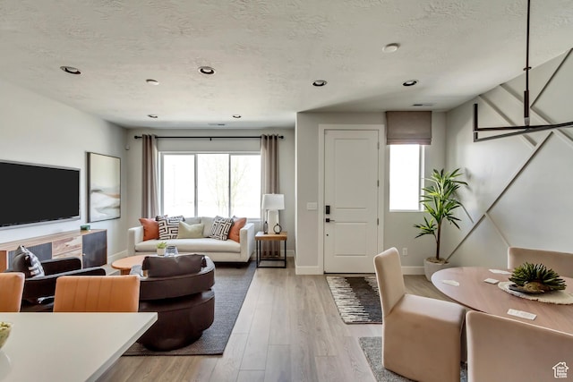 living area featuring a wealth of natural light, light wood-style floors, and a textured ceiling