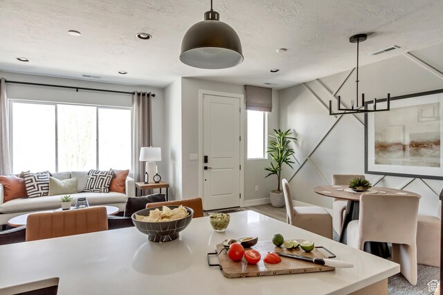 living area with a notable chandelier, a healthy amount of sunlight, and a textured ceiling
