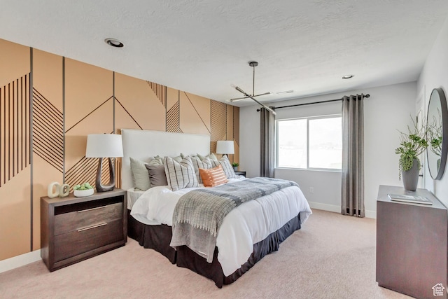 bedroom featuring light colored carpet, baseboards, and a textured ceiling