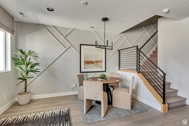 dining space featuring visible vents, baseboards, wood finished floors, and stairs