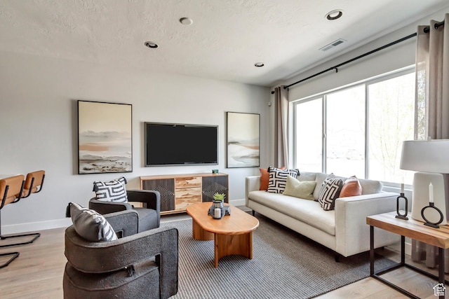 living room with wood finished floors, baseboards, visible vents, recessed lighting, and a textured ceiling