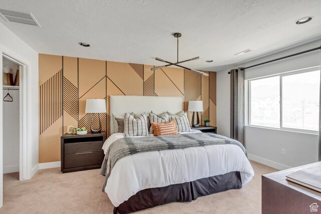 bedroom with visible vents, baseboards, light colored carpet, and a textured ceiling
