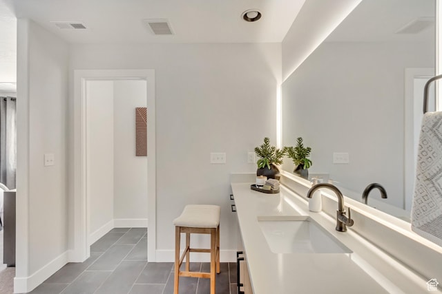 bathroom featuring a sink, visible vents, baseboards, and double vanity