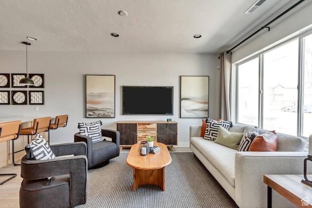 living area with visible vents, recessed lighting, a textured ceiling, and baseboards