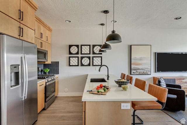 kitchen with light wood-style flooring, light brown cabinets, a sink, stainless steel appliances, and light countertops