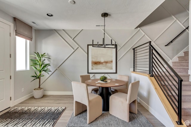 dining room featuring visible vents, stairs, baseboards, and wood finished floors