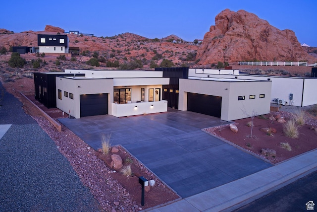 view of front of home featuring concrete driveway, a mountain view, a garage, and stucco siding