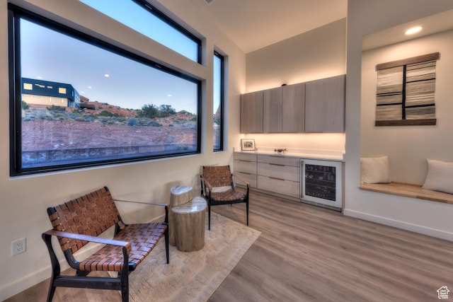 sitting room with wine cooler, wood finished floors, baseboards, and a dry bar